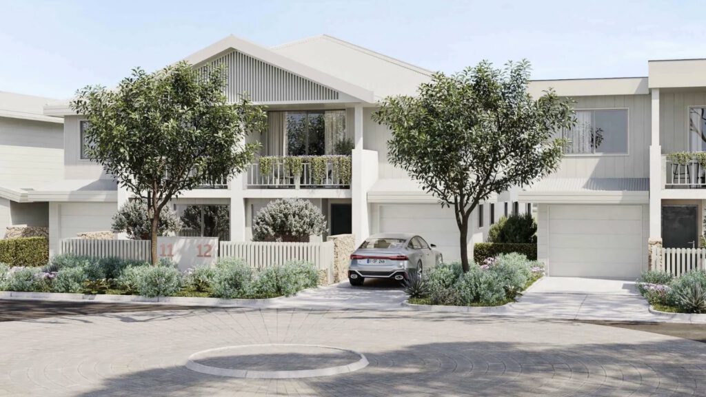 Modern two-storey white house with large windows, balconies, and two trees in front garden. A silver car is parked in the drive near the garage, surrounded by neatly landscaped bushes and greenery. The sky is clear and sunny.